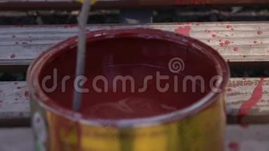 搅拌罐子里的红色油漆，把油漆混合在木棍里，慢动作