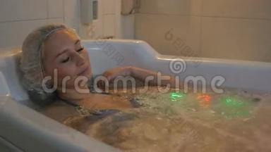 年轻女子用五颜六色的灯光在水浴中放松