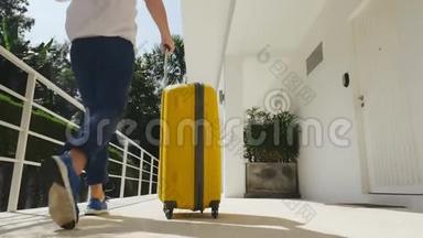 商人带着一个黄色的手提箱离开现代的房子。