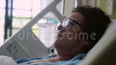戴眼镜的老年妇女躺在病床上，滴着氧气罩。 心电监护仪的改变