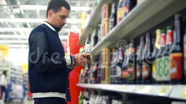 一个人在购物中心的货架上，拿着饮料和啤酒。 他拿着啤酒罐
