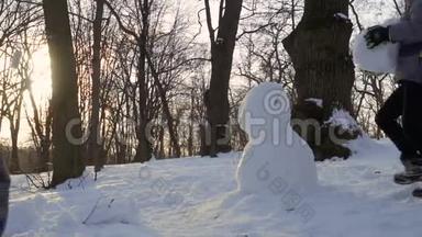 男孩在冬季公园里慢慢堆雪人