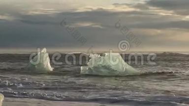冰山和<strong>蓝白</strong>冰块在波浪上滚动。 波浪在冰上破碎。 日出时在海滩冲浪。 伊塞拉