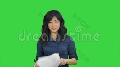 自信的亚洲女商人把纸撕成小块，扔到绿色屏幕上，Chroma键