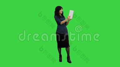 使用绿色屏幕上的平板电脑进行视频聊天的亚洲女士，Chroma键