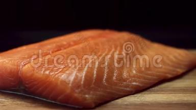 将<strong>新鲜</strong>美味的<strong>三文鱼</strong>牛排放在木切割板上，隔离在黑色背景上。 生的红鱼片