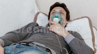 使用雾化器和吸入器进行治疗。 躺在沙发上的年轻人通过吸入器面罩吸入。 前景。
