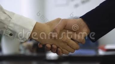 办公室背景下的握手特写。 良好的商业交易与握手建立了伙伴关系。 两个同事