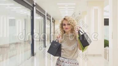 漂亮的女孩带着购物袋在<strong>商场</strong>里跳跃，微笑着，对他们的购买<strong>感</strong>到高兴。