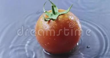 一个人在一个灰色的玻璃背景上，用水覆盖着一个西红柿。 慢动作2k视频推240fps