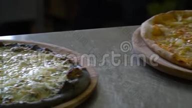 一家餐馆。 披萨饼。 桌子上的厨房里有三个现成的披萨。 它们又新鲜又热。 特写镜头。 慢慢