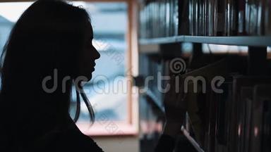 图书馆书架前一个女孩看书的剪影