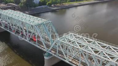 从空中俯瞰铁路大桥，上面有一列移动的火车，穿过流经一个主要城市的河流