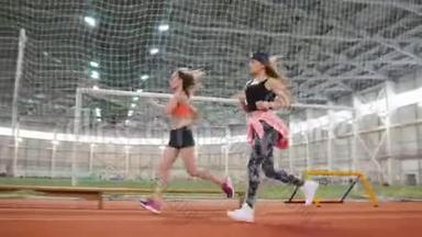 两个年轻的女运动员在室内运动场上奔跑
