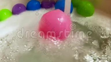 粉<strong>红色</strong>塑料球在浴缸里的水流中<strong>滚动</strong>，动作缓慢