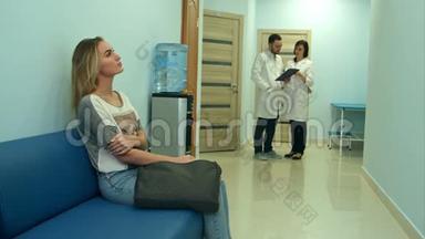 女病人在医院大厅等候，两名医生在咨询