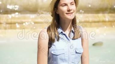 快乐的游客戴着帽子坐在老黄的喷泉上，水流不息。 欧洲度假的女孩