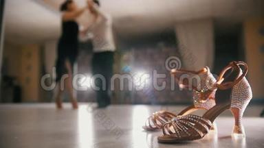 模糊的职业男人和女人在工作室里穿着服装跳舞拉丁舞，在前台穿着交际鞋，动作缓慢