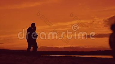 日落时分，一对夫妇在海滩上<strong>牵手散步</strong>的剪影。 在夕阳的灯光下，在海滨快乐的男人和女孩