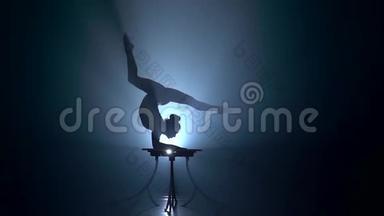 桌子上的Acrobat显示了她手上的把戏。 烟雾背景。 慢<strong>动作</strong>。 <strong>剪影</strong>