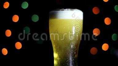 黑色背景上的一杯冷啤酒，有<strong>彩灯</strong>。 啤酒在玻璃杯里起泡。
