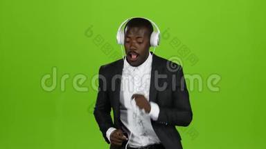 非裔美国人<strong>跳动</strong>拉丁语，在耳机里听音乐。 绿色屏幕