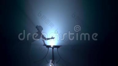 桌子上的Acrobat显示了站在她手上的技巧。 烟雾背景。 慢动作。 剪影