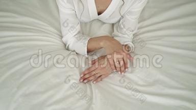 女孩躺在床上，摸着她的手。 白色床上的女孩。 新娘正在抚摸她的手。