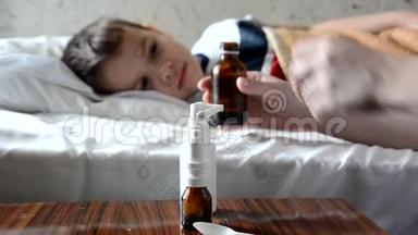 婴儿药和生病的孩子男孩躺在沙发上发烧，休息在家里，妈妈给她的儿子吃药