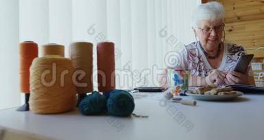 坐在桌子上操作手机的老妇人