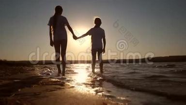 孩子们走在海滩上，脚踩在红色傍晚日落的水面上。