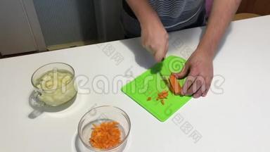 一个人切蔬菜做饭。 用刀子在切割板上，<strong>打碎</strong>胡萝卜并将其转移到容器中。