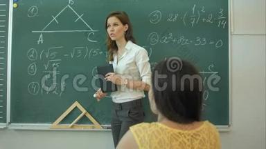 聪明自信的女学生在教室里用黑板写数学