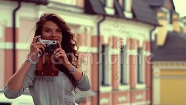迷人的旅游女孩带着旧相机在街上拍照，