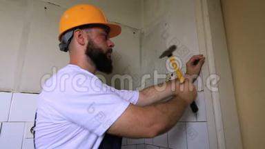 建筑工人和建筑工人用黄色锤子敲击，并在施工现场将钉子钉在厨房门的木墙上。