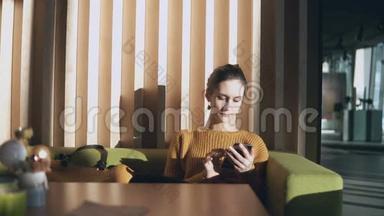 年轻迷人的女人坐在酒店里拿着智能手机。 女商人在大厅的沙发<strong>上上</strong>网。