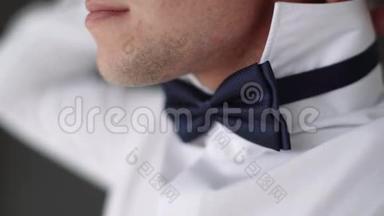 那个人把衬衫特写的领子伸直。 一个穿白衬衫的人。