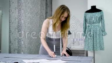 年轻的女设计师，脖子上挂着胶带线，站在制衣工作室，用<strong>粉笔</strong>和规则画<strong>线条</strong>