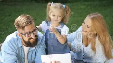 快乐女孩和<strong>爸爸妈妈</strong>在阳光明媚的夏日草地上玩得开心的家庭画像