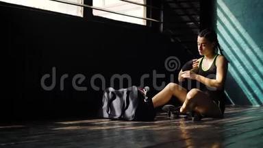 惊慌失措的年轻美女<strong>坐在地板上</strong>，用黑色拳击包裹在俱乐部里的手。