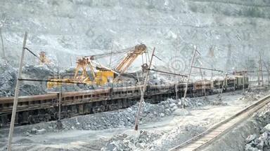 挖掘机和铁路用矿石。挖掘机在露天矿背景下充满矿石轨道车。 采矿重型运输