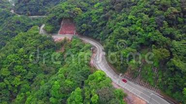 台湾绿树林中的汽车沿着弯曲的蛇形道路行驶。 鸟瞰图