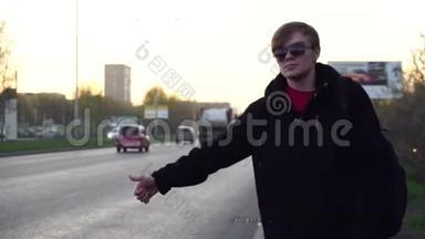 有魅力的人正在路附近乘出租车。 年轻的快乐男子在欧洲的街道上搭出租车。 高加索人的肖像