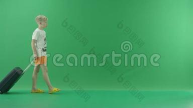 一个穿着便装的金发<strong>小</strong>男孩在夏天和一个<strong>小东西</strong>一起散步。 他走在绿色屏幕上