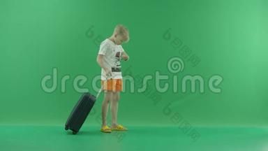 一个穿着便装的金发小男孩在夏天和一个小东西一起散步。 他走在绿色屏幕上