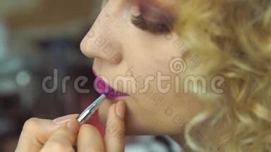 化妆师在画室给漂亮的小女孩画红唇妆特写。红唇