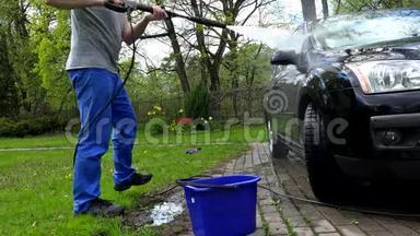男职工在露天用动力喷水冲洗汽车..