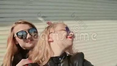 两个年轻漂亮的女朋友戴着太阳镜，脸上<strong>洋溢</strong>着乐趣和风骚，在镜头前摆姿势。 做什么
