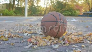 秋天在球场上打黄叶篮球。 相机从左边。 篮球出现在图片中。