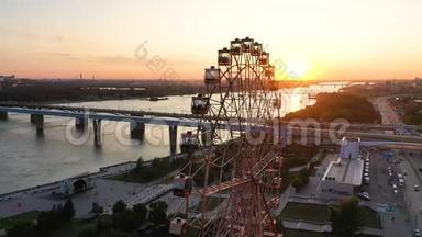 在河和城市景观上，无人机可以看到游乐园里五颜六色的摩天轮。 大型摩天轮游乐园